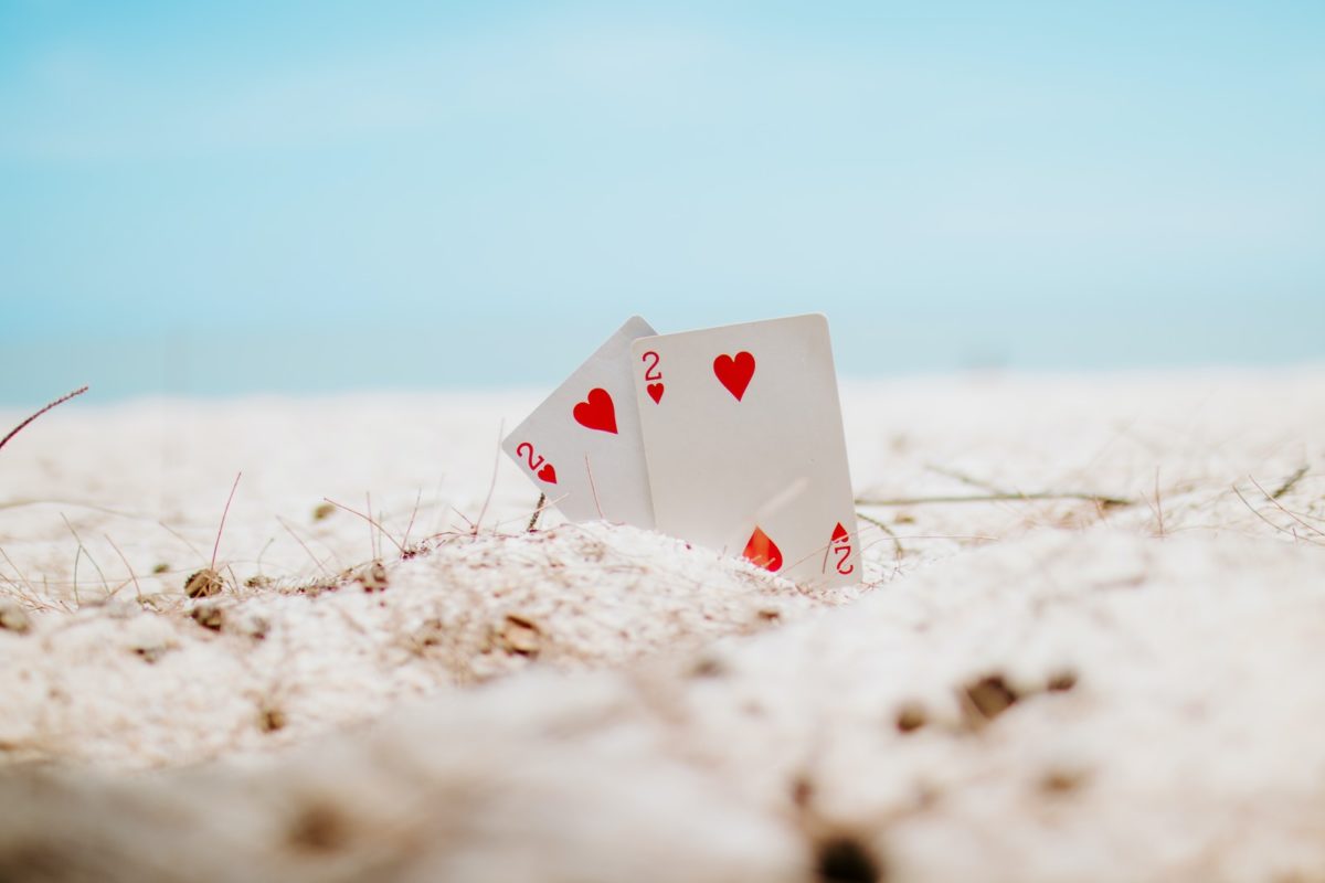 white and red heart playing card on white sand during daytime